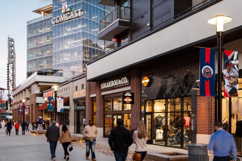 Pedestrians passing storefronts and residential frontage on a walkway at The Battery Atlanta.
